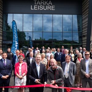 Eddie the Eagle flies in to sample Devon's first ever endless ski slope A group of people gather outside the Tarka Leisure building for a red ribbon-cutting ceremony.