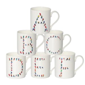 Six white mugs arranged in a pyramid, each displaying a letter of the alphabet formed by tiny colourful skier figures.