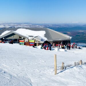 Adaptive skiing and snowboarding in Cairngorm, where new magic carpets are making all the difference Skiers gather outside a modern mountain lodge flying the Scottish saltire, with vast snowy hills stretching into the distance.