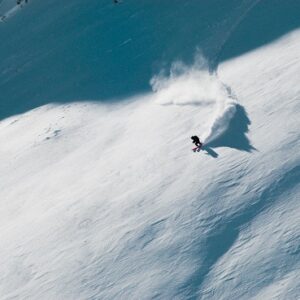 Banff adventure film festival storms the UK A snowboarder carves down a vast, untouched snow-covered mountainside, sending up a spray of powder.