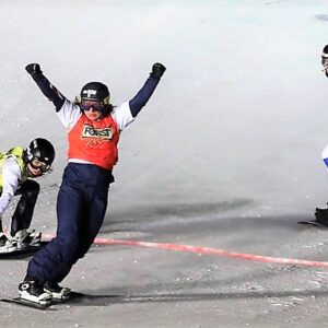 Impressive month for GB Snowsports skiers and snowboarders A snowboarder in an orange "Forum" race bib raises both arms in victory as two competitors in green and yellow bibs race past on the snow course.