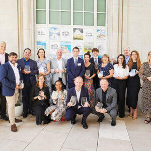 Peak Retreats wins Best Ski Operator at Telegraph Travel Awards 2023 A group of people pose indoors holding glass awards in front of "Travel Weekly Travel Awards" posters.