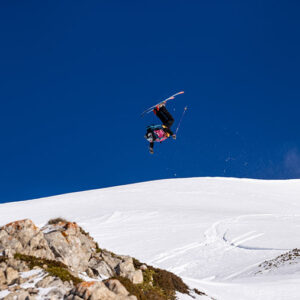No Limits Bruson Freeride Week returns to Verbier, Switzerland Skier mid-flip high above a snowy mountainside beneath a deep blue sky.