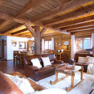 Sociable ski trips for the solo traveller Spacious wooden-beamed chalet lounge with leather sofas, sheepskin cushions, and a chess set on a rustic coffee table.