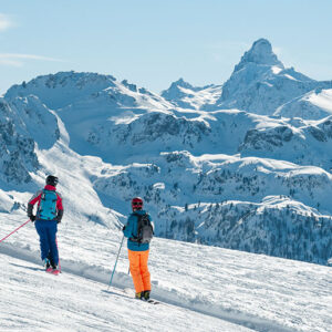 Vialattea set to open for its longest season to date Two skiers in colourful gear descend a snowy slope with a sharp, pyramidal snow-covered peak rising in the distance.