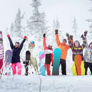 Six resorts great for an Easter Ski holiday Seven snowboarders stand in deep snow with arms raised, their colourful boards planted upright against a backdrop of snow-laden pine trees.
