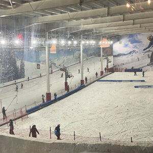 Hitting the slopes for the first time Skiers and snowboarders descend an indoor snow slope beneath a large Nelson snowboard poster.