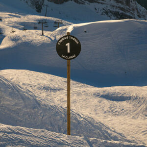 La Clusaz unveils new slope named after legend Candide Thovex A signpost reading "CANDIDE THOVEX 1 LA CLUSAZ" stands on a snowy piste with chairlifts visible in the background.