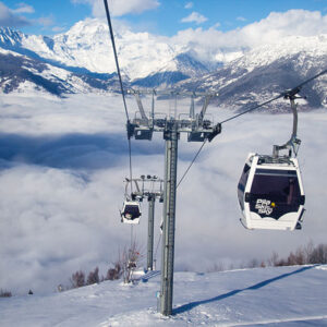 Gondolas branded "Pip's Sky" ascend above a sea of clouds toward snow-capped Alpine peaks.