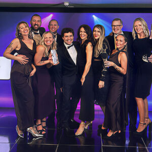 Active holiday company wins gold at British Travel Awards A group of formally dressed people smile and hold trophies on stage at the British Travel Awards 2025, with Neilson Beachclubs·Ski branding visible behind them.