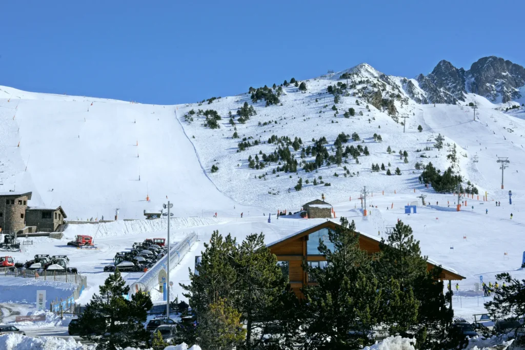 Skiers on a wide sunlit piste at Pas de la Casa in the Grandvalira ski area, Andorra